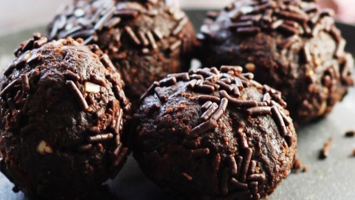 Schokoladenkugeln liegen auf einem Teller, streuen Schokoladenglasur und werden als preiswerte Mitbringsel serviert.