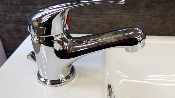 Der gl&auml;nzende Wasserhahn im Bad strahlt Sauberkeit aus, w&auml;hrend er sanft Wasser ins Waschbecken flie&szlig;en l&auml;sst.