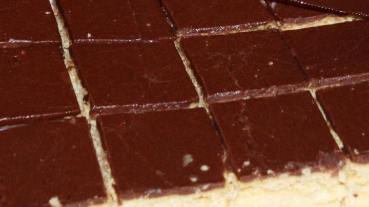 Ein gl&auml;nzender Schokoguss &uuml;berzogen ein Schneidbrett mit gleichm&auml;&szlig;igen Keksst&uuml;cken, bereit zum Servieren.