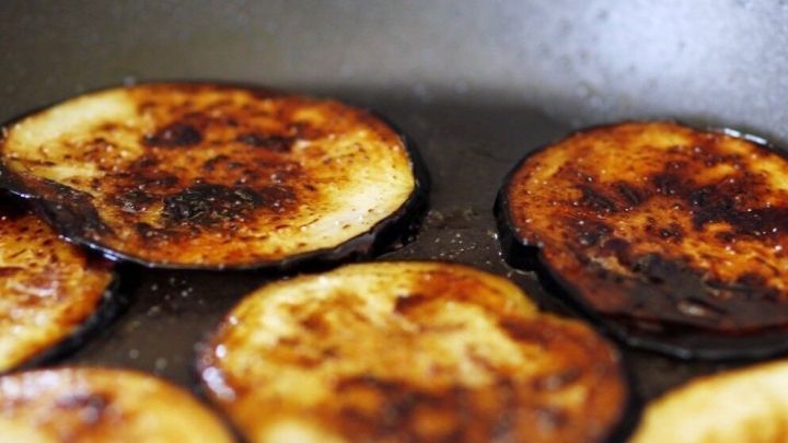 Verkohlte Auberginenringe braten in einer Pfanne, leicht angebrannt und goldbraun gef&auml;rbt, im K&uuml;chenkontext.