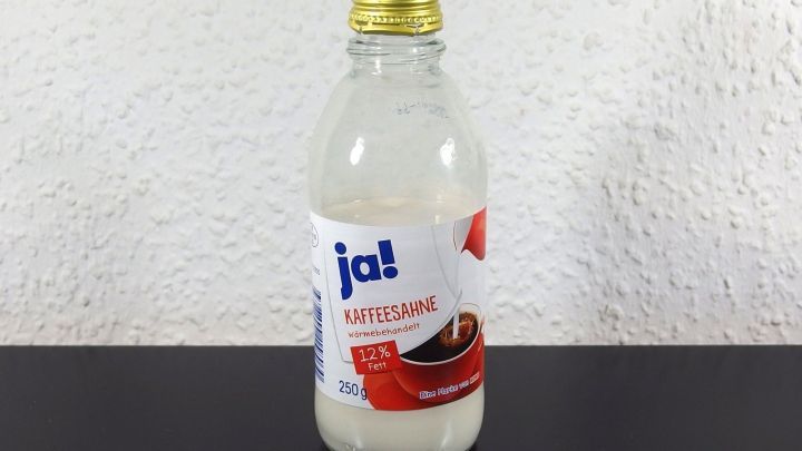 Eine Flasche mit light Sahne steht auf einem Tisch. Sie zeigt den Schriftzug "ja!" und eine rote Verpackungsgrafik.