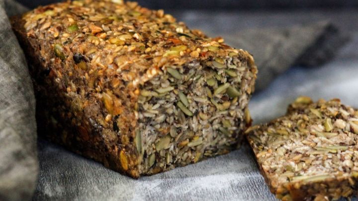 Ein knuspriges, selbstgebackenes Brot aus verschiedenen Gem&uuml;sesorten liegt auf einem Teller, umgeben von dunklem Hintergrund.