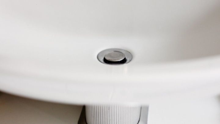 Ein Abfluss in einem Waschbecken, der m&ouml;glicherweise verstopft ist, steht im Fokus der Aufnahme.