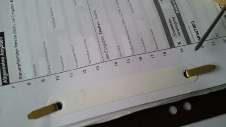 Ein Heftstreifen fixiert mehrere Bl&auml;tter Papier auf einem Tisch, um die Dokumente ordentlich zu organisieren und zu stabilisieren.