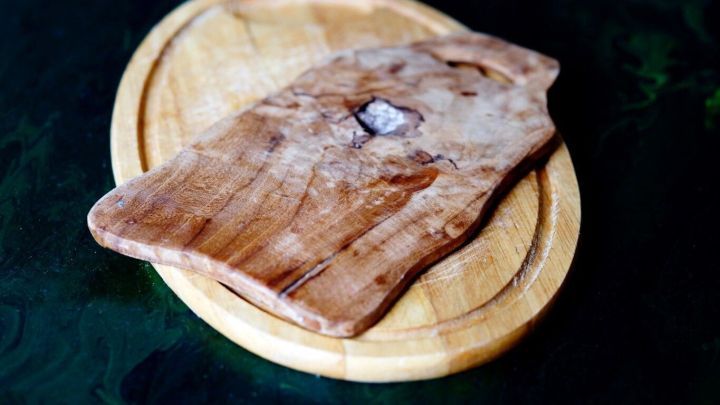 Ein Holzschneidebrettchen liegt auf einem anderen Holzbrett, bereit zur Auffrischung beim Tischler.