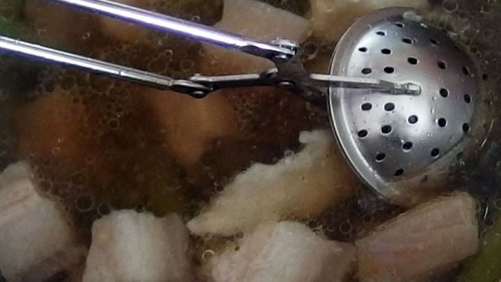 Ein Tee-Ei wird in einen Topf mit Suppe getaucht, um den versalzenen Geschmack zu mildern. St&uuml;cke schwimmen im Wasser.