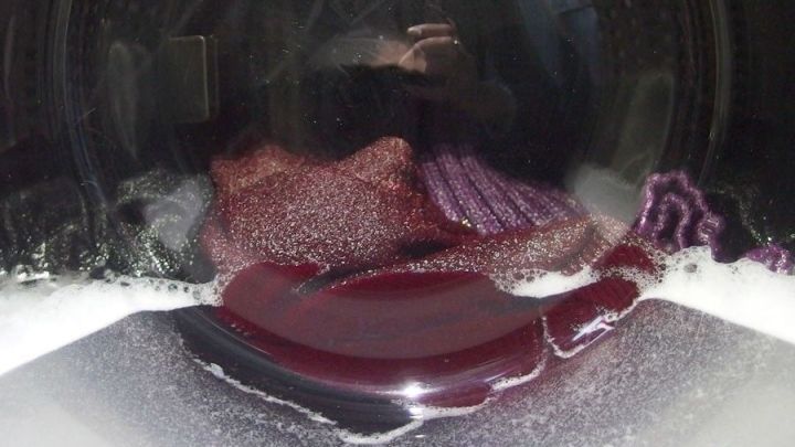 Eine Waschmaschine w&auml;scht bunte W&auml;sche in Seifenlauge, um die Lebensdauer der Waschmaschine zu verl&auml;ngern.