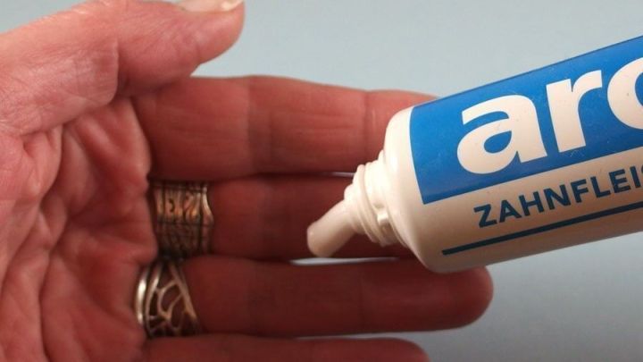 Eine Hand h&auml;lt eine Tube Zahnpasta, w&auml;hrend sie etwas davon auf die Hand auftr&auml;gt, um Zwiebel- und Knoblauchgeruch zu entfernen.