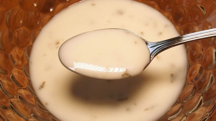 Zitronen-Buttermilch-Dressing wird mit einem L&ouml;ffel aus einer Sch&uuml;ssel aufgenommen, um einen cremigen Dip zu zeigen.