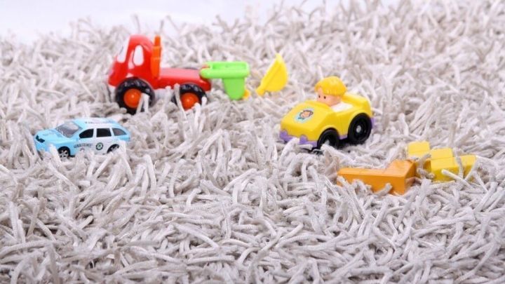 Bunte Spielzeugautos liegen verstreut auf einem Teppich, w&auml;hrend Kinderzimmer aufger&auml;umt werden. Ordnung ohne Knatsch.