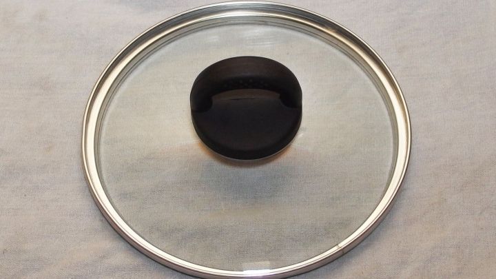 Ein gl&auml;nzender Pfannendeckel liegt auf einer neutralen Oberfl&auml;che und zeigt die Reinigung eines K&uuml;chenutensils ohne Streifen.