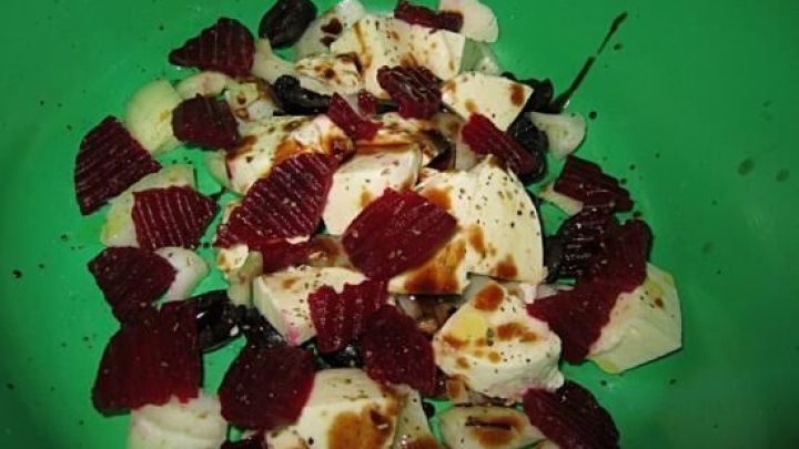 Mozzarella-W&uuml;rfel liegen bunt gemischt auf einem gr&uuml;nen Teller, umgeben von roter Beete, verfeinert mit Balsamico.