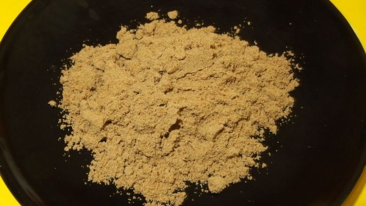 Feine Heilerde liegt auf einem schwarzen Teller, bereit zur Verwendung f&uuml;r die Zahnzwischenraumpolitur bei engen Z&auml;hnen.