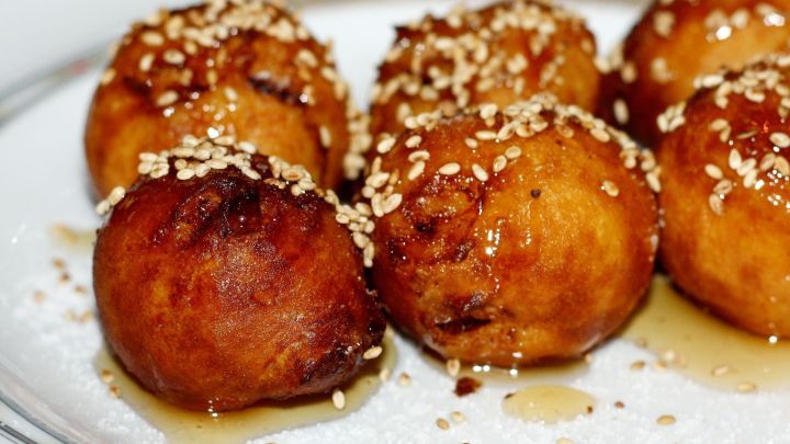 Frittierte Bananenkugeln liegen auf einem Teller, goldbraun und knusprig, umgeben von einer Zuckerschicht.