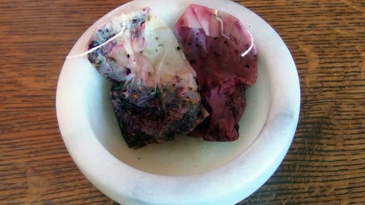 Zwei Teebeutel liegen in einer kleinen Schale aus Marmor, die auf einem Holztisch steht, bereit f&uuml;r die Zubereitung.