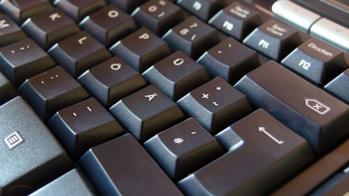 Eine PC-Tastatur liegt nah, die Tasten sind leicht verschmutzt und zeigen Spuren der Nutzung in einem Arbeitsumfeld.