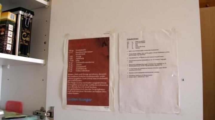 An der Schrankt&uuml;r h&auml;ngen Rezepte, die zum Kochen anregen, umgeben von K&uuml;chenutensilien und Zutaten.