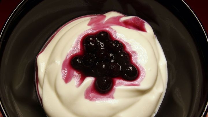 Cremiger Sahnejoghurt in einer Sch&uuml;ssel, garniert mit dunkler Fruchtso&szlig;e, in einer gem&uuml;tlichen K&uuml;chenszene.