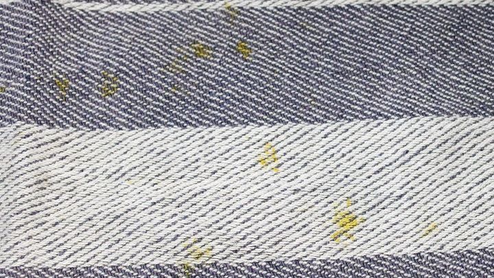 Auf einer gestreiften Oberfl&auml;che sind gelbe Karottenflecken sichtbar, die durch eine gezielte Reinigung mit Baby&ouml;l entfernt werden sollen.