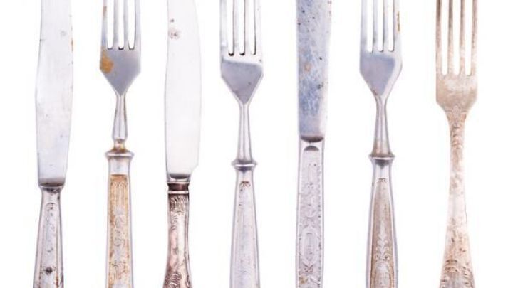 Edelstahlbesteck mit Roststellen liegt ordentlich nebeneinander. Die rostigen Fl&auml;chen sind deutlich sichtbar, was Pflege bedarf.