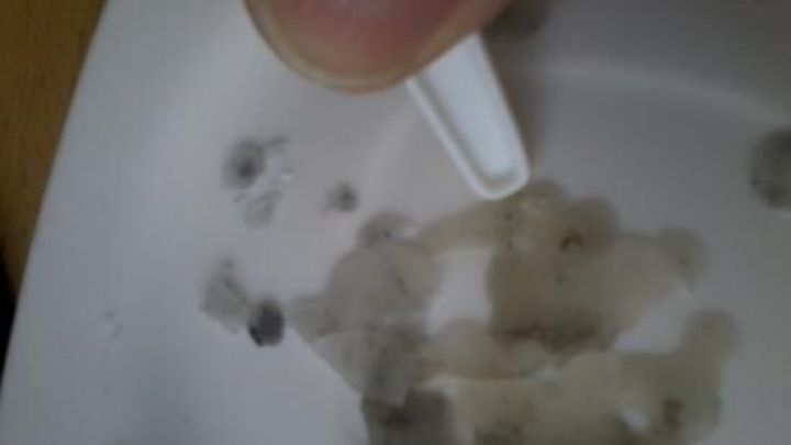 Ein Plastikspatel entfernt Wachs von einer harten, wei&szlig;en Oberfl&auml;che. Der Hintergrund ist leicht unscharf. Keine Text.