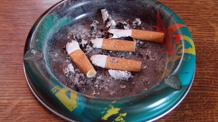 Ein Aschenbecher mit mehreren zerbrochenen Zigarettenreste und Asche, symbolisiert den Kampf, rauchfrei zu werden.