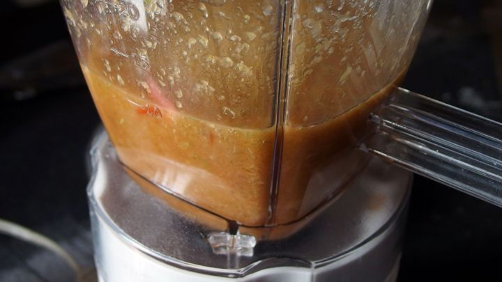 Ein Mixer mit einer cremigen Salatmischung arbeitet in einer K&uuml;che, um ein gesundes Getr&auml;nk zuzubereiten.