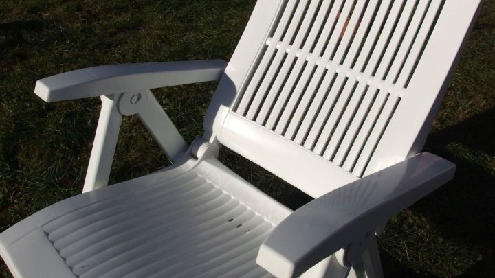 Ein wei&szlig;er Kunststoffstuhl steht im Garten und gl&auml;nzt frisch gereinigt, bereit f&uuml;r den n&auml;chsten Einsatz im Freien.
