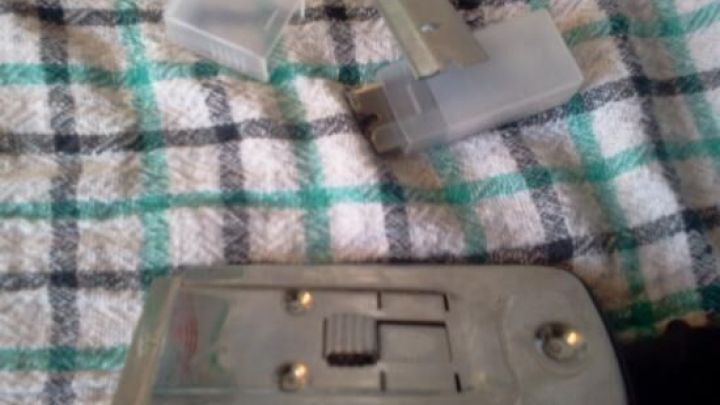 Ein Fensterschaber liegt auf einem karierten Tuch, w&auml;hrend Klingenhalterungen daneben liegen, bereit zur Nutzung.