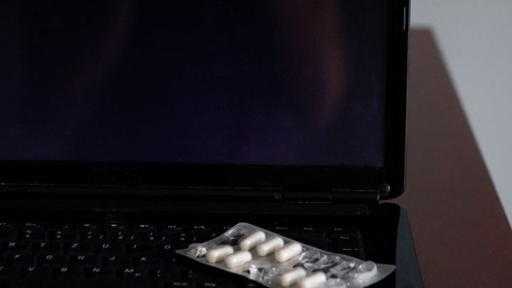 Ein Tablettenblister liegt vor einem Laptop, dessen Bildschirm eine Fehlermeldung zeigt, und ein Haftnotiz weist auf "Opa anrufen!" hin.