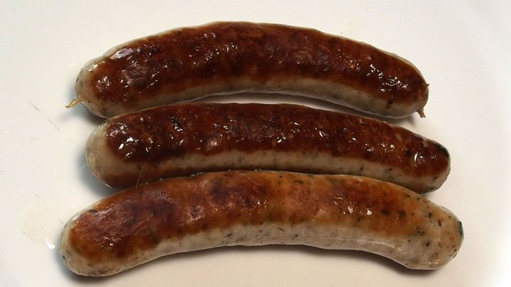 Drei gebratene Bratw&uuml;rste liegen auf einem wei&szlig;en Teller, zur Aufbewahrung nach dem Grillen bereit.