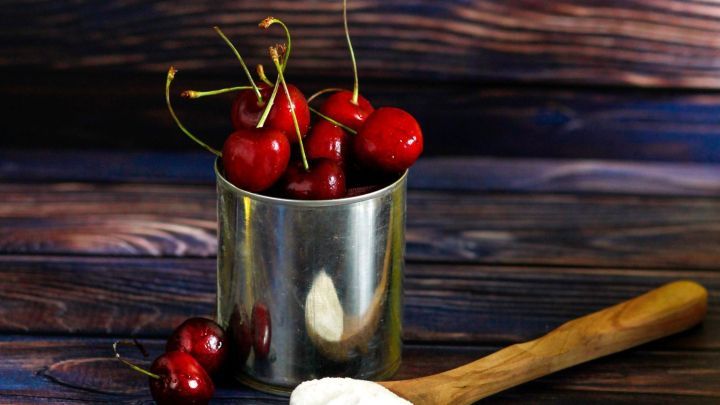 In einer Metallb&uuml;chse liegen frische saure Kirschen, daneben ein Holzl&ouml;ffel mit Haus-Natron zur Verwendung.