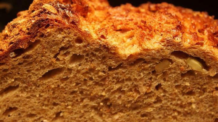 Ein frisch gebackenes Brot mit knuspriger Kruste liegt auf einem Tisch, umgeben von warmem Licht und Holzdetails.