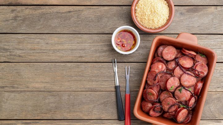 Scheiben von Jagdwurst liegen in einer Sch&uuml;ssel, w&auml;hrend sie mit Dips und einer Beilage aus Semmelbr&ouml;seln angerichtet sind.