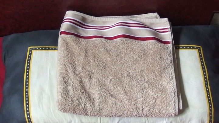 Ein Handtuch liegt ordentlich gefaltet auf einem Kissen, bereit zur Schmerzlinderung bei Kopf-/Zahn-/Ohrenschmerzen.