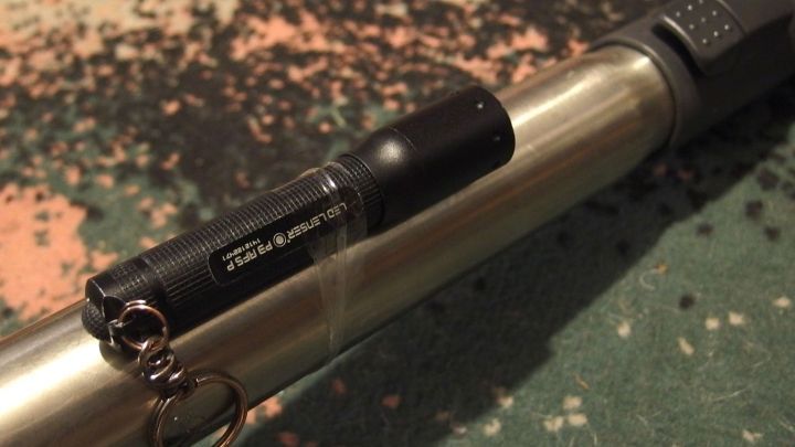 Ein Handstaubsauger liegt auf einem Teppich, w&auml;hrend eine kleine Taschenlampe an ihm befestigt ist, die Licht in dunkle Ecken bringt.