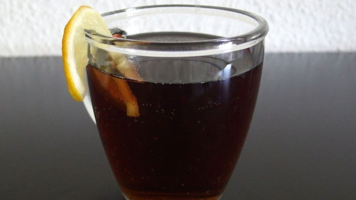 Ein Glas kalter Tee mit Zitrone steht auf einem dunklen Tisch, erfrischend und bereit zum Genie&szlig;en.