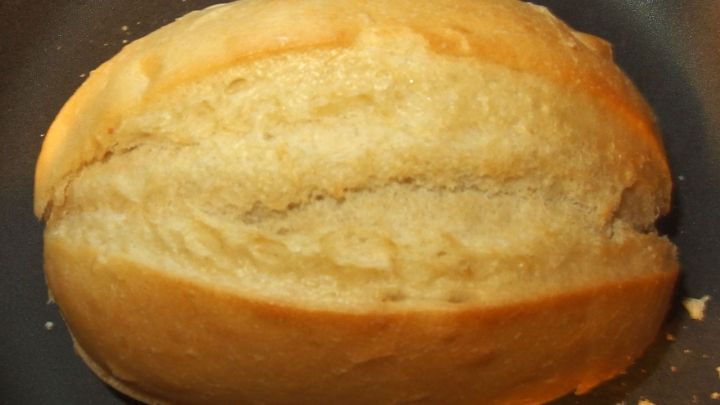 Ein knuspriges Aufbackbr&ouml;tchen liegt in einer Pfanne und wird leicht ger&ouml;stet, um seine goldene Kruste zu entfalten.