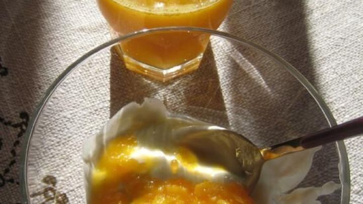 Ein Glas frisch gepresster Orangensaft steht neben einer Sch&uuml;ssel mit Fruchtfleisch von orangenen Zitrusfr&uuml;chten.