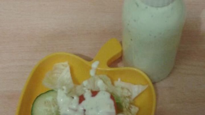 Ein Fl&auml;schchen mit Salatdressing steht neben einem gelben Sch&uuml;sselchen, das mit frischem Salat gef&uuml;llt ist.