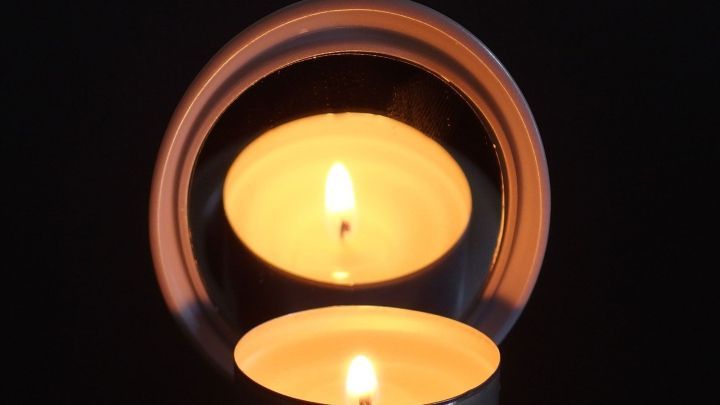 Zwei Kerzen leuchten sanft, umgeben von einem dunklen Hintergrund, schaffen festliche Beleuchtung und eine gem&uuml;tliche Atmosph&auml;re.