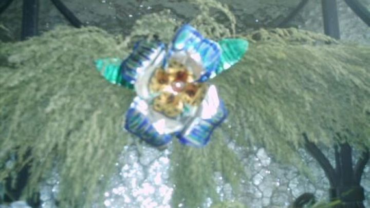 Bunte Blumen aus Alu-Futtersch&auml;lchen liegen auf einem Tisch, umgeben von gr&uuml;nem Gras und einem rustikalen Hintergrund.