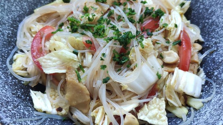 Ein bunter Glasnudelsalat mit d&uuml;nnen Nudeln, H&auml;hnchenst&uuml;cken und frischem Gem&uuml;se in einer dekorativen Schale.