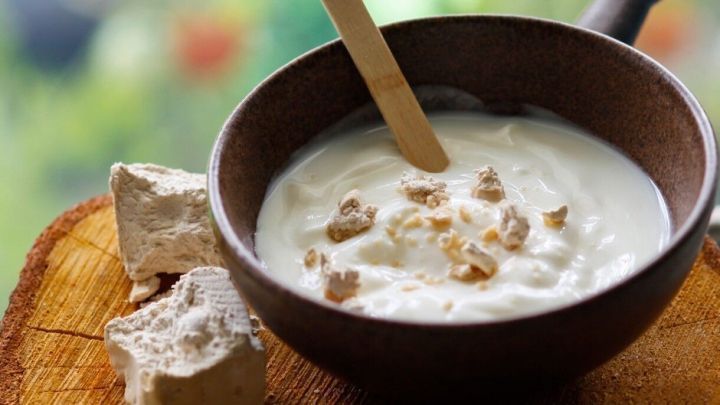 Eine Sch&uuml;ssel mit Hefemaske steht auf einem Holzbrett, w&auml;hrend die Maske cremig und verziert aussieht.