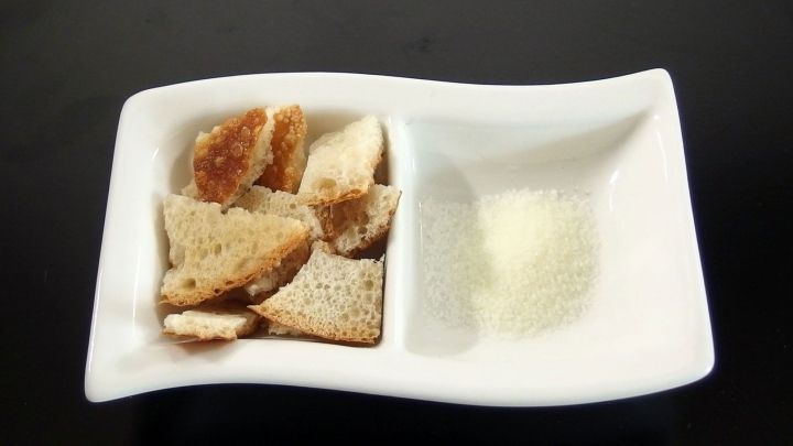 Eine wei&szlig;e Schale mit Brotw&uuml;rfeln und Gew&uuml;rzen, bereit zum Reinigen und Zubereiten von Speisen.