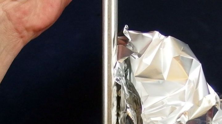 Ein Hand h&auml;lt ein Chromst&uuml;ck, w&auml;hrend die andere Hand ein St&uuml;ck Alufolie benutzt, um Rostflecken zu entfernen.