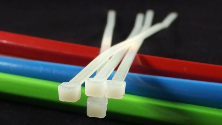 Wei&szlig;e Kabelbinder liegen auf bunten Kabeln, bereit zum Verl&auml;ngern, um verschiedene Objekte zusammenzufassen.