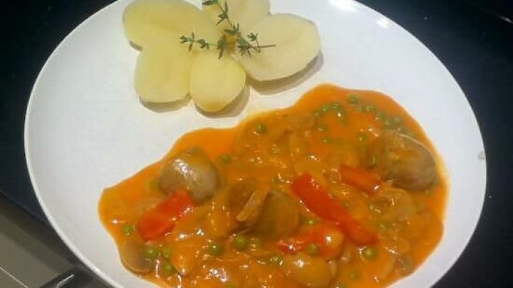 Auf einem wei&szlig;en Teller liegt ein w&uuml;rziges D&auml;nisches Bratwurstgericht mit buntem Gem&uuml;se und einer Blumenkartoffel-Beilage.