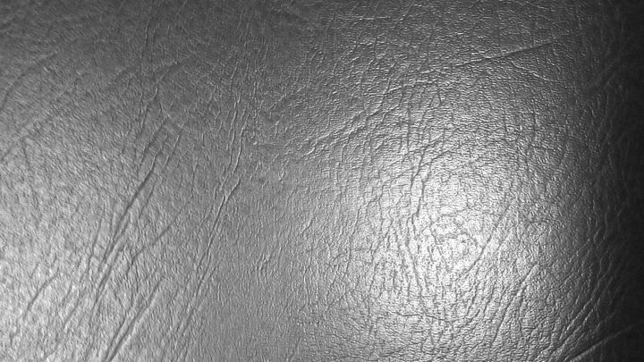 Ein glattes, schwarzes Lederm&ouml;belst&uuml;ck liegt im Fokus, es reflektiert leicht das Licht in einem neutralen Raum.