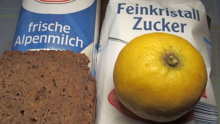 Frische Alpenmilch, Zucker und eine Zitrone liegen nebeneinander auf einem Tisch, ideal gegen Katerbeschwerden.